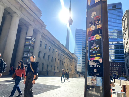 Vancity Postering's poster installed at Toronto's Union Station with the CN tower in the background and pedestrians passing by. One of SCM's great advertising services